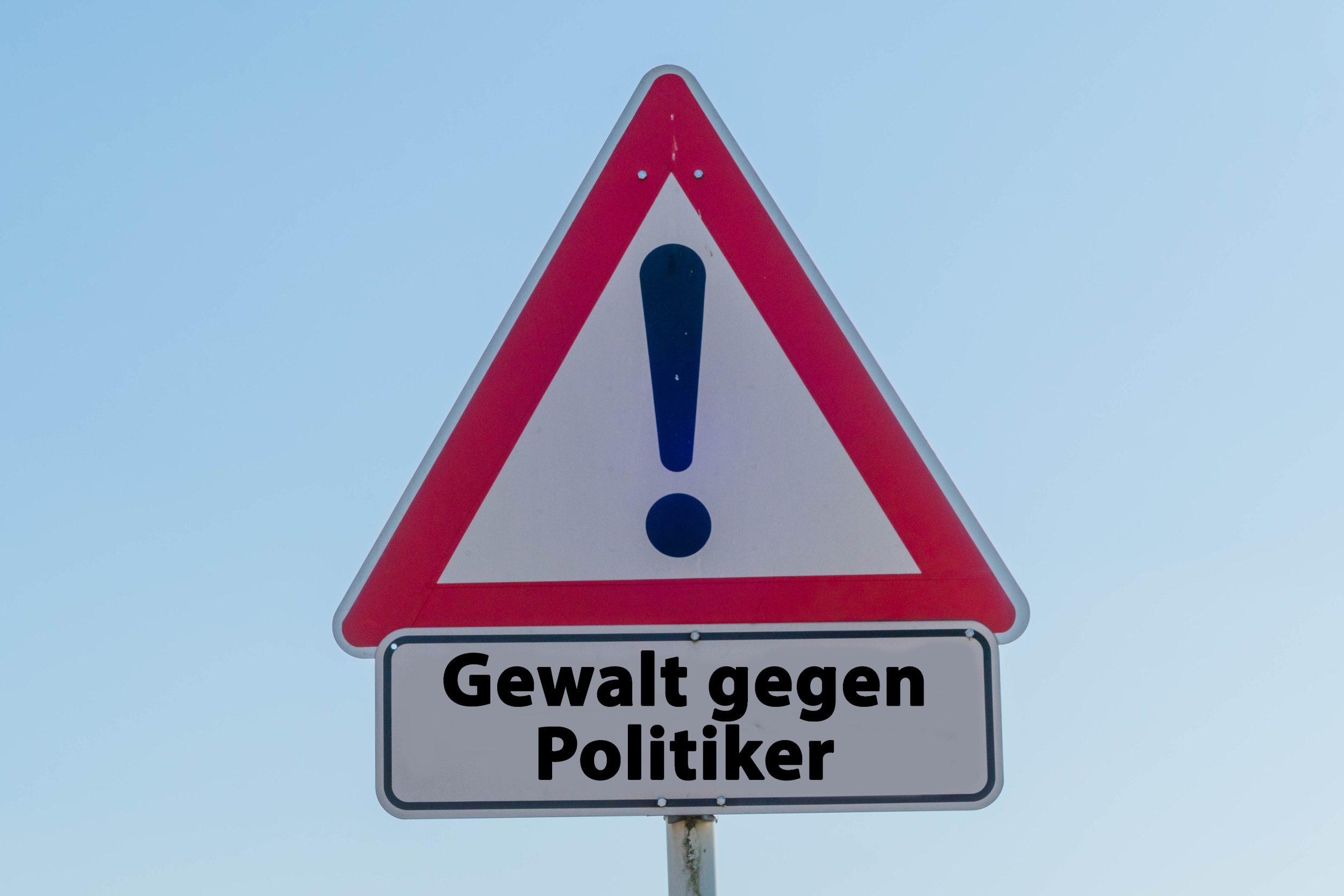 Das Bild zeigt ein Verkehrsschild mit einem Ausrufezeichen und dem Schriftzug "Gewalt gegen Politiker".