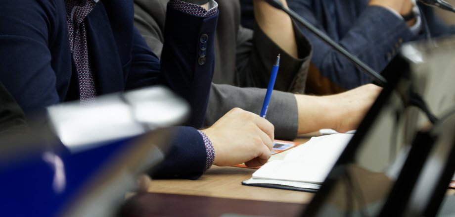 Teilnehmer einer Sitzung mit Laptops und Stiften hören einem Redner zu.