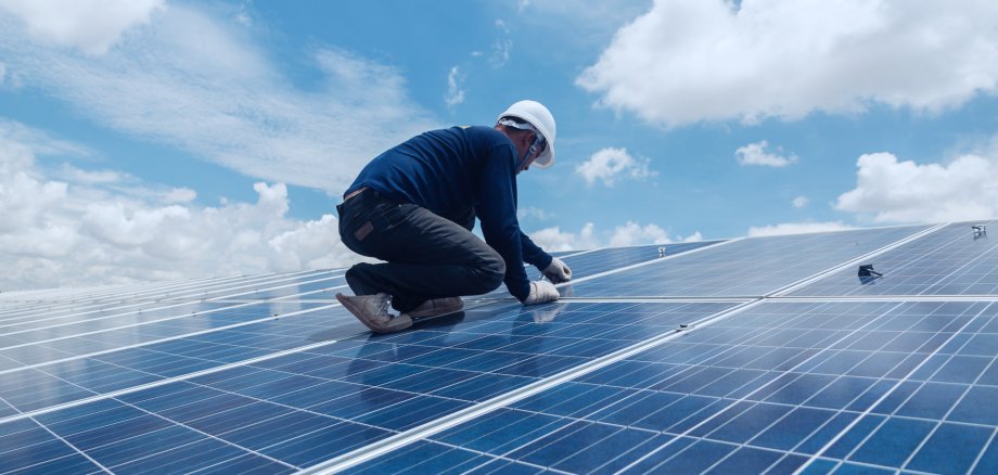 Handwerker montiert eine Solaranlage auf einem Dach.
