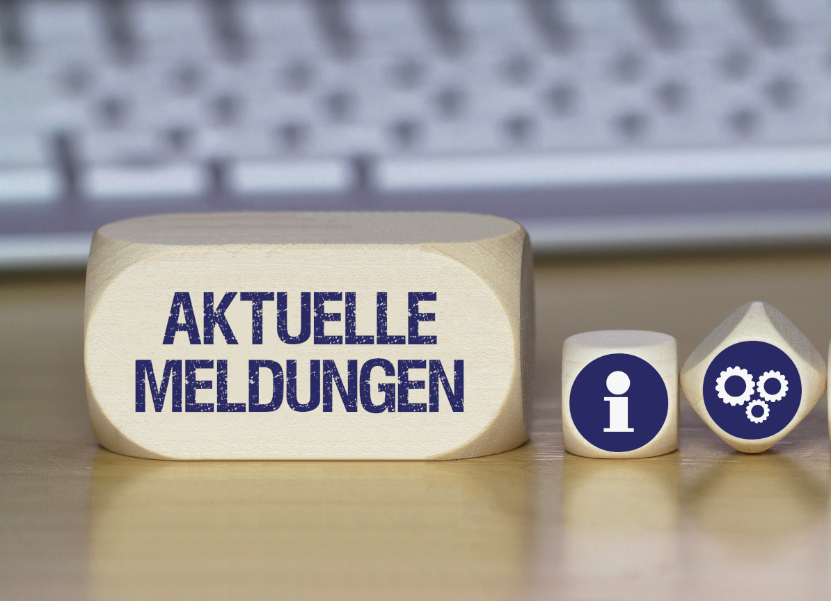 Holzwürfel mit der Aufschrift "AKUELLE MELDUNGEN", daneben Symbole für Information und Einstellungen, im Hintergrund eine Computertastatur.