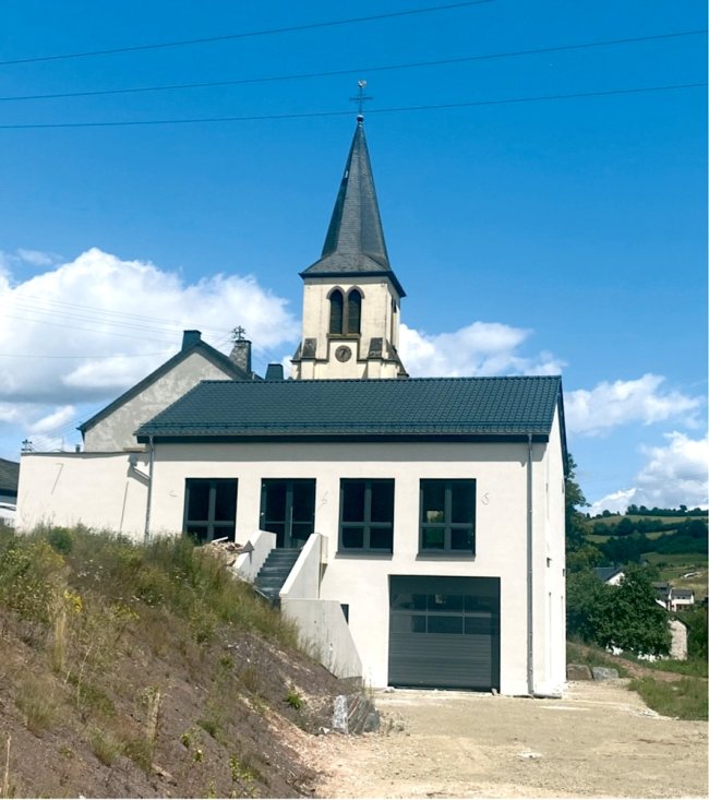 Das neue Dorfgemeinschaftshaus der Ortsgemeinde Lasel. Im Hintergrund sieht man den Turm der Kirche St. Helena.