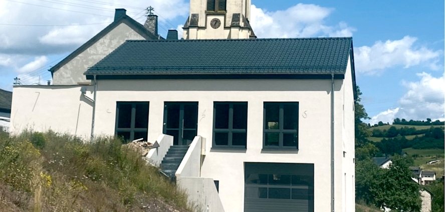 Das neue Dorfgemeinschaftshaus der Ortsgemeinde Lasel. Im Hintergrund sieht man den Turm der Kirche St. Helena.