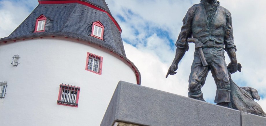 H.PIEL /Ein berühmter Sohn der Stadt: Der Räuber „Schinderhannes“ ist mit einem Denkmal vor dem nach ihm benannten Turm verewigt. Das Bauwerk dient als Veranstaltungsraum und ist Teil des Hunsrück-Museums.