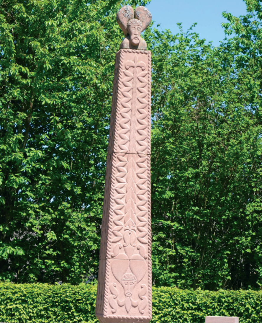 Obelisk vor Hecke und Bäumen