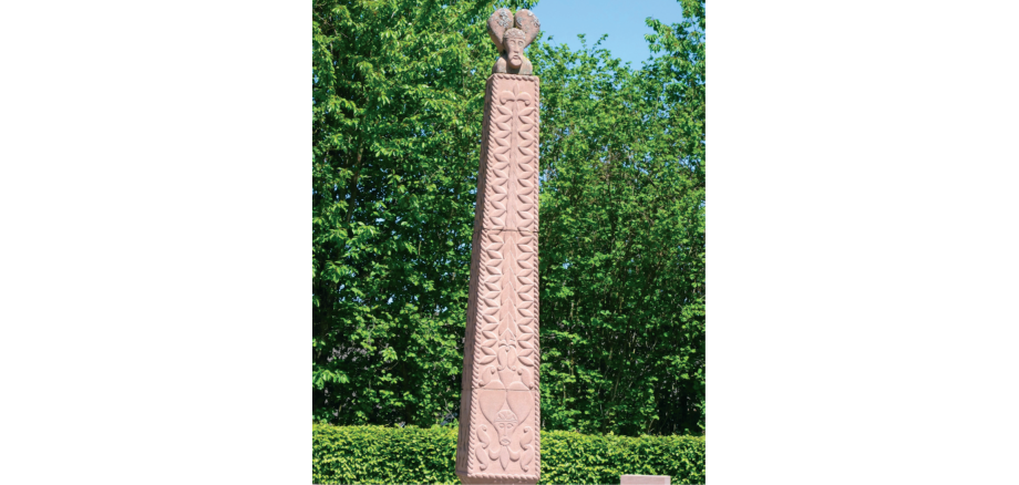 Obelisk vor Hecke und Bäumen