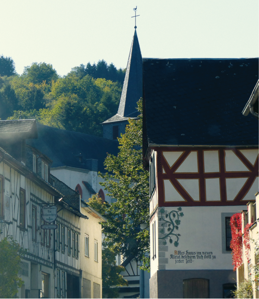 Blick in eine Gasse in der Ortsgemeinde Oberdiebach mit Fachwerkhäusern und einer Kirche.