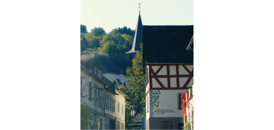 In einem Seitental des linksrheinischen Mittelrheintals liegt zwischen Koblenz und Mainz die Ortsgemeinde Oberdiebach. Blick in eine Gasse in der Ortsgemeinde Oberdiebach mit Fachwerkhäusern und einer Kirche.