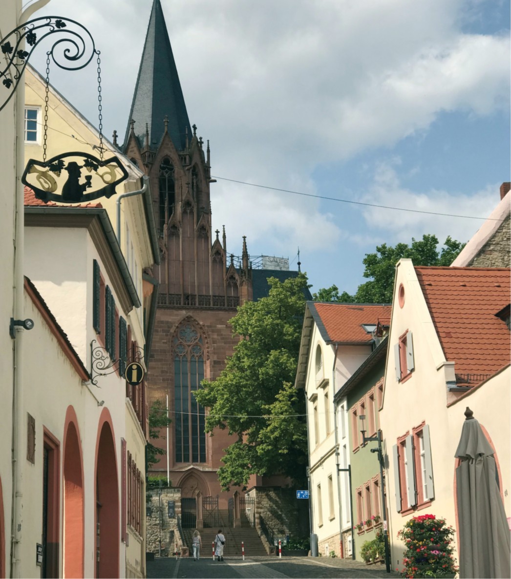 Die Katharinenkirche in Oppenheim vor blauem Himmel und umgeben von historischen Häusern.