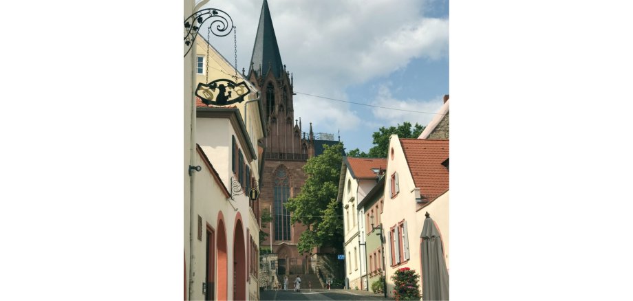 Die Katharinenkirche in Oppenheim vor blauem Himmel und umgeben von historischen Häusern.