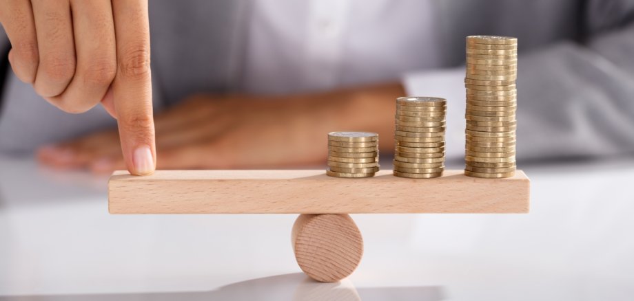 Businessperson Balancing Coins On Wooden Seesaw