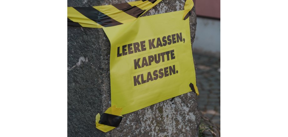 Gelbes Schild mit der Aufschrift "Leere Kassen, kaputte Klassen".