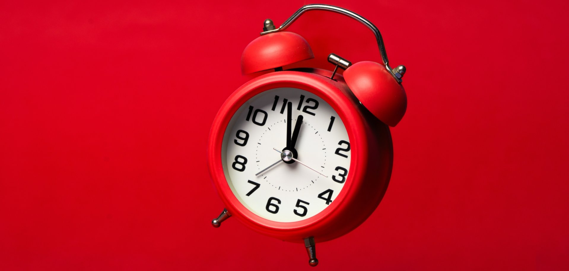 Roter Wecker: Zeiger stehen auf 5 vor 12.