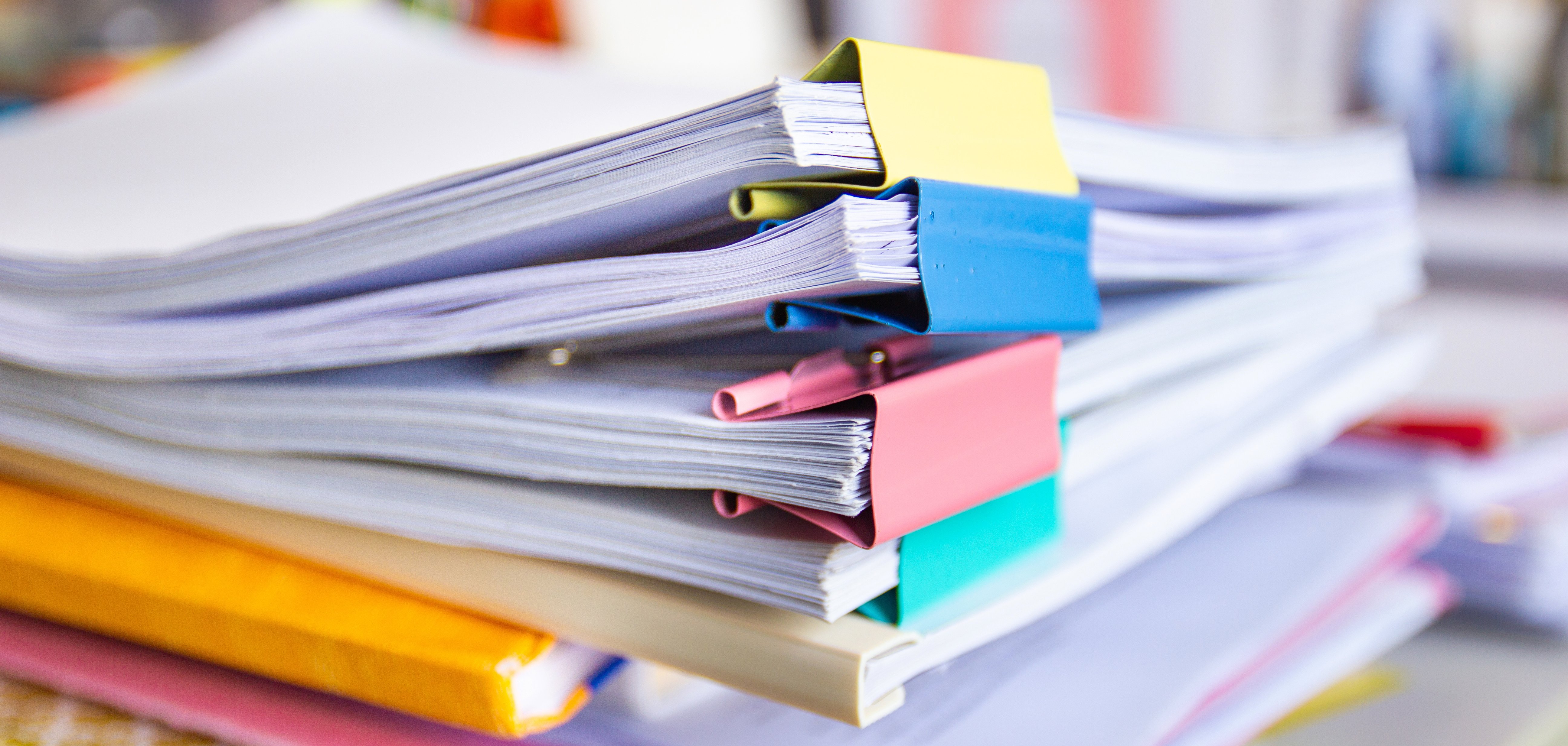 Das Foto zeigt einen Stapel Aktenordner auf einem Tisch in einem Büro.