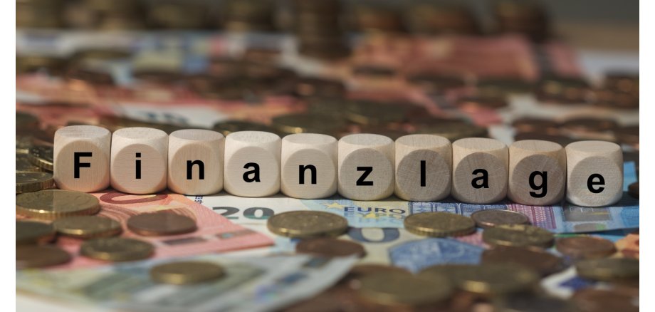 Finanzlage Euroscheine und Münzen. Darauf Würfel mit der Aufschrift "Finanzlage"