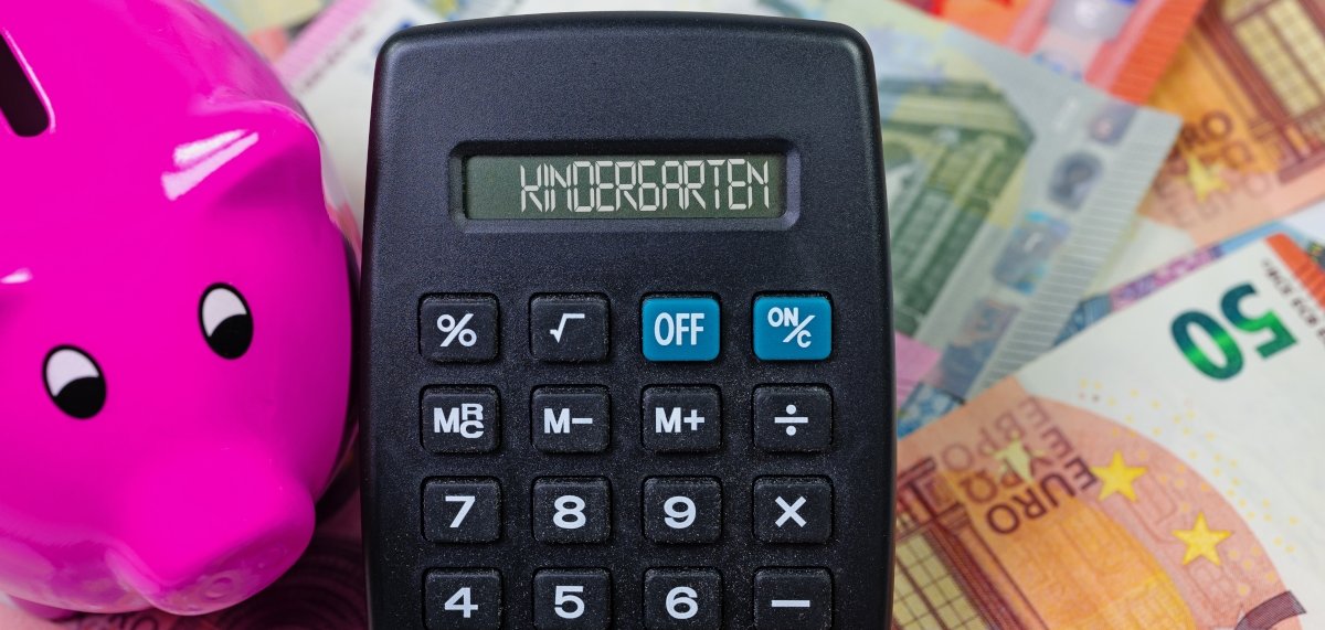 Taschenrechner mit dem Wort Kindergarten im Display, Geldscheine und ein Sparschwein.