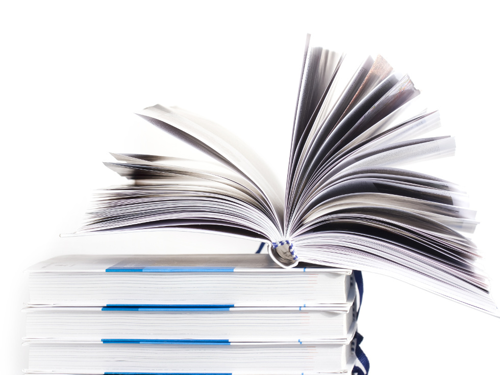 Ein Buch liegt aufgefächert auf einem kleinen Bücherstapel.