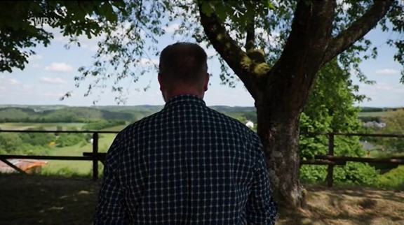 Bürgermeister Markus Göbel von hinten. Er steht unter einem großen Baum und blickt auf eine grüne Hügellandschaft. Oben links ist das Logo „SWR“ eingeblendet.