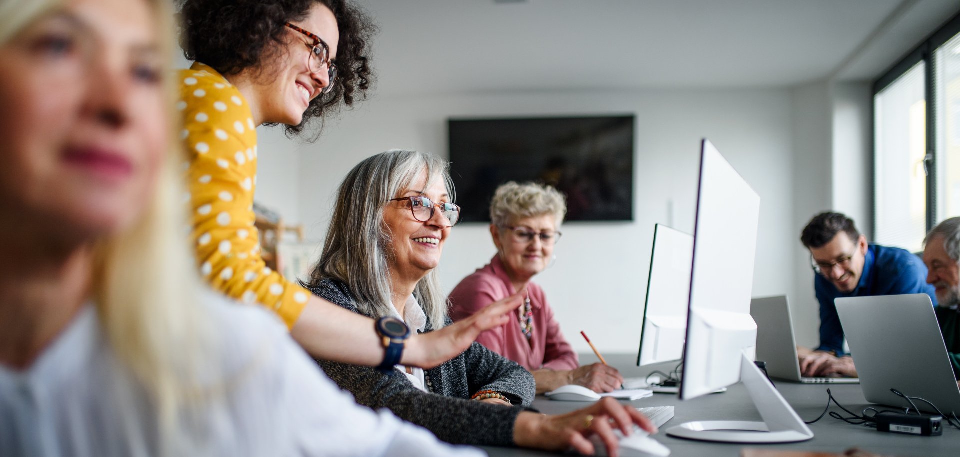 Eine Gruppe gut gelaunter Senioren besucht einen Computer- und Technologiekurs.