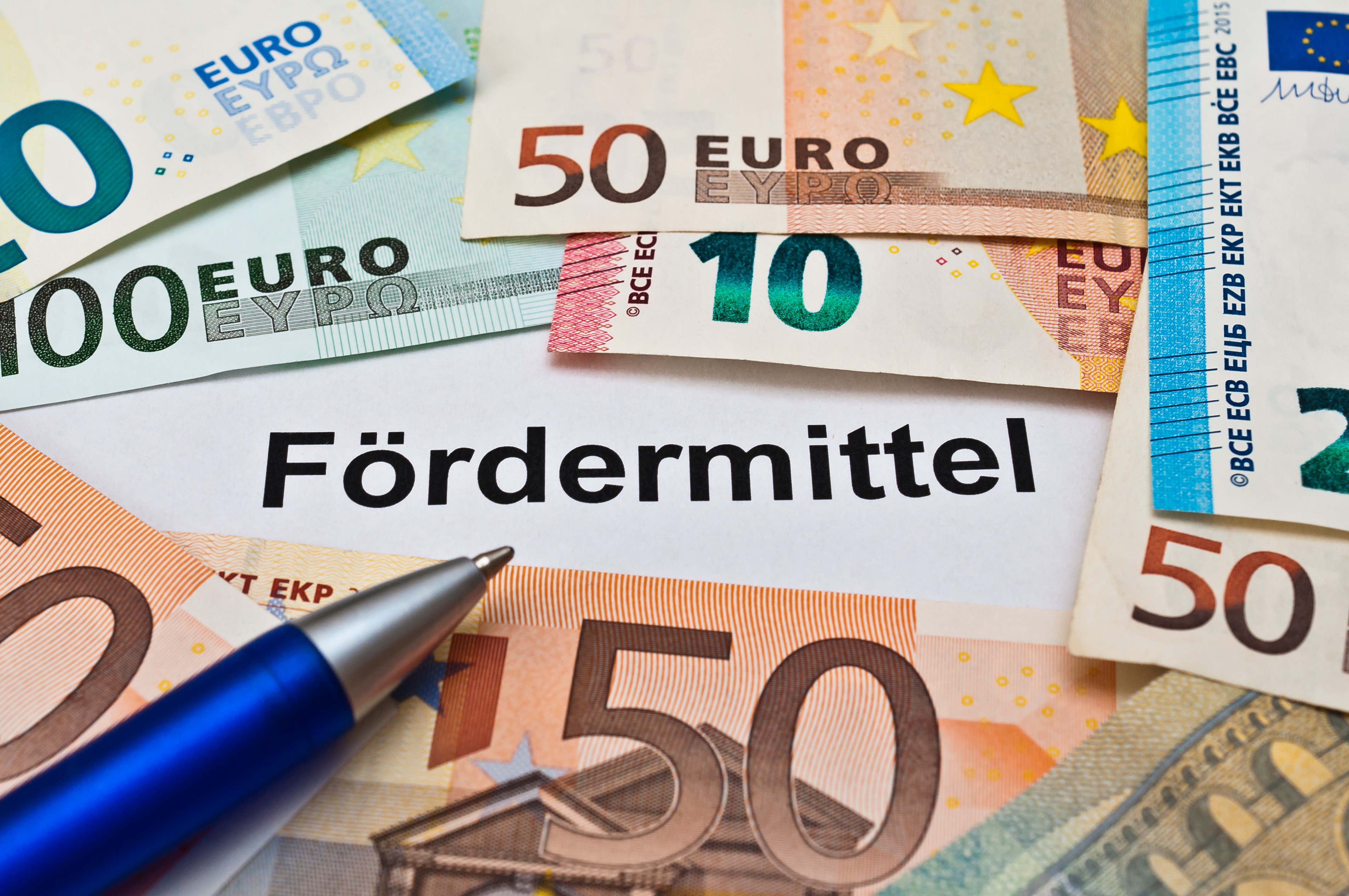 Das Bild zeigt mehrere Euroscheine. In der Mitte steht der Schriftzug "Fördermittel".