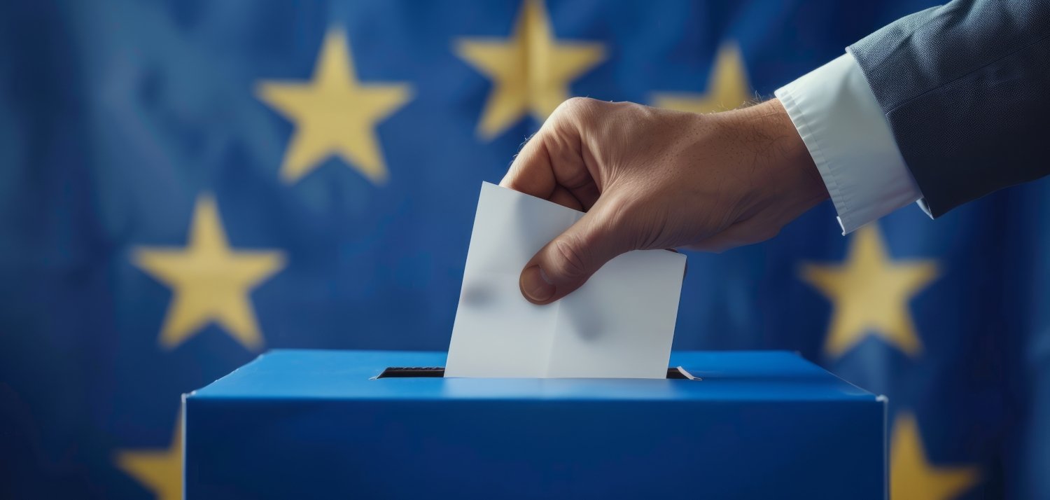 Hand mit Briefumschlag und Wahlurne vor einer Europaflagge