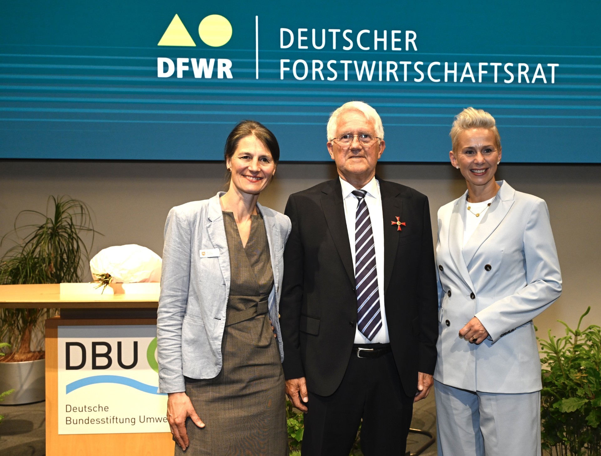 Ministerin Miriam Staudte, Georg Schirmbeck und die parl. Staatsekretärin Silvia Breher auf der Bühne beim feierlichen Festakt in Osnabrück.