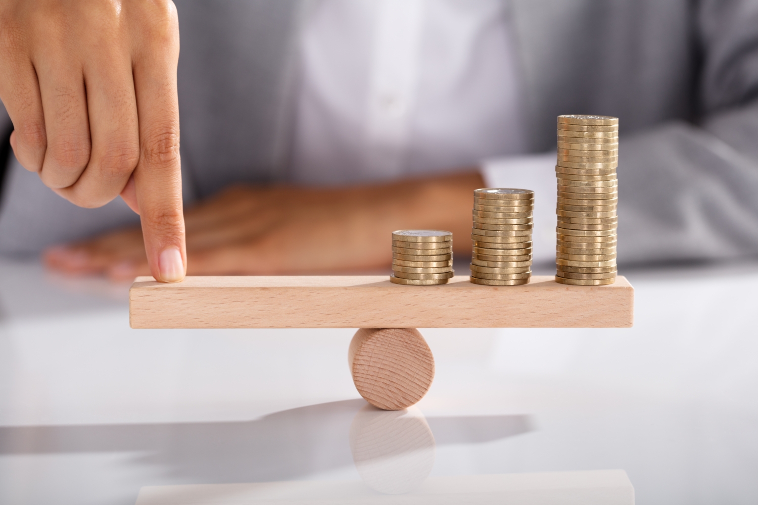 Businessperson Balancing Coins On Wooden Seesaw