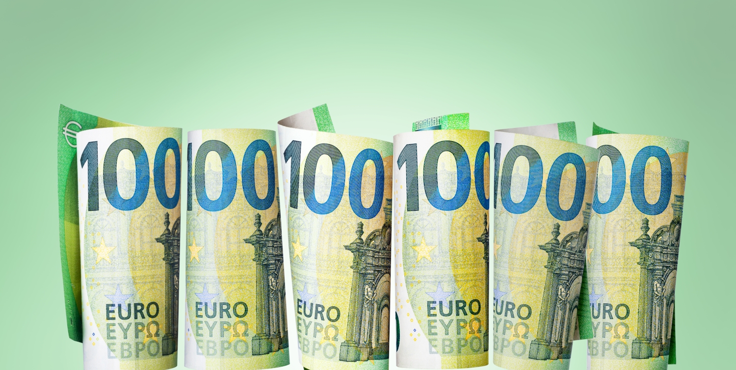 Gerollte Hundert-Euro-Scheine stehen senkrecht vor grünem Hintergrund.