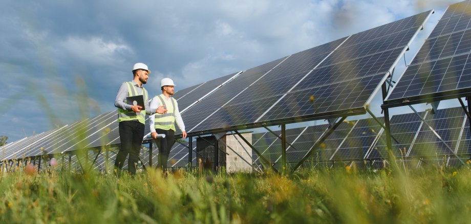 Engineers inspecting large solar power panels in field