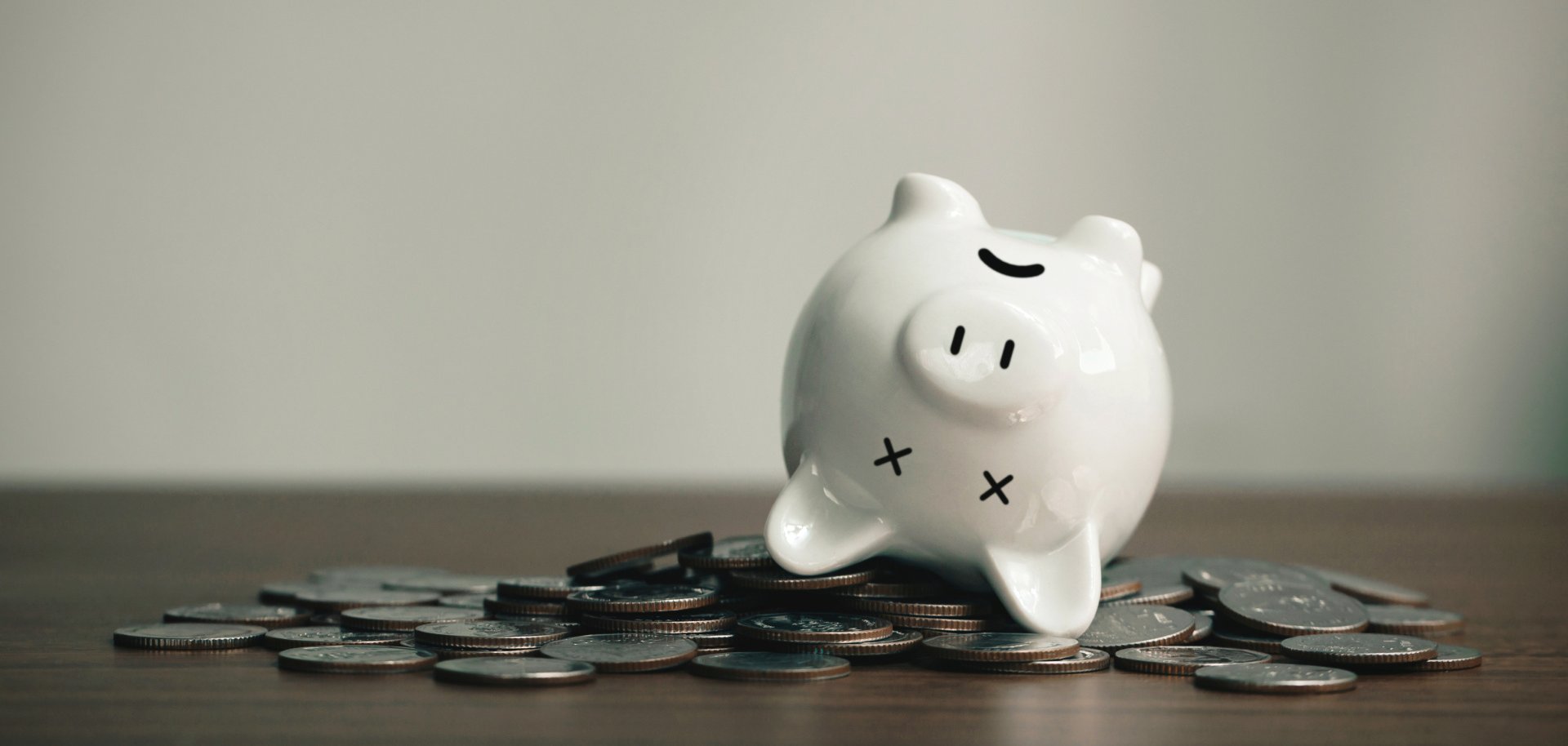 Sparschwein liegt auf dem Rücken auf Münzen.