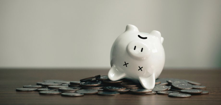 Sparschwein liegt auf dem Rücken auf Münzen.