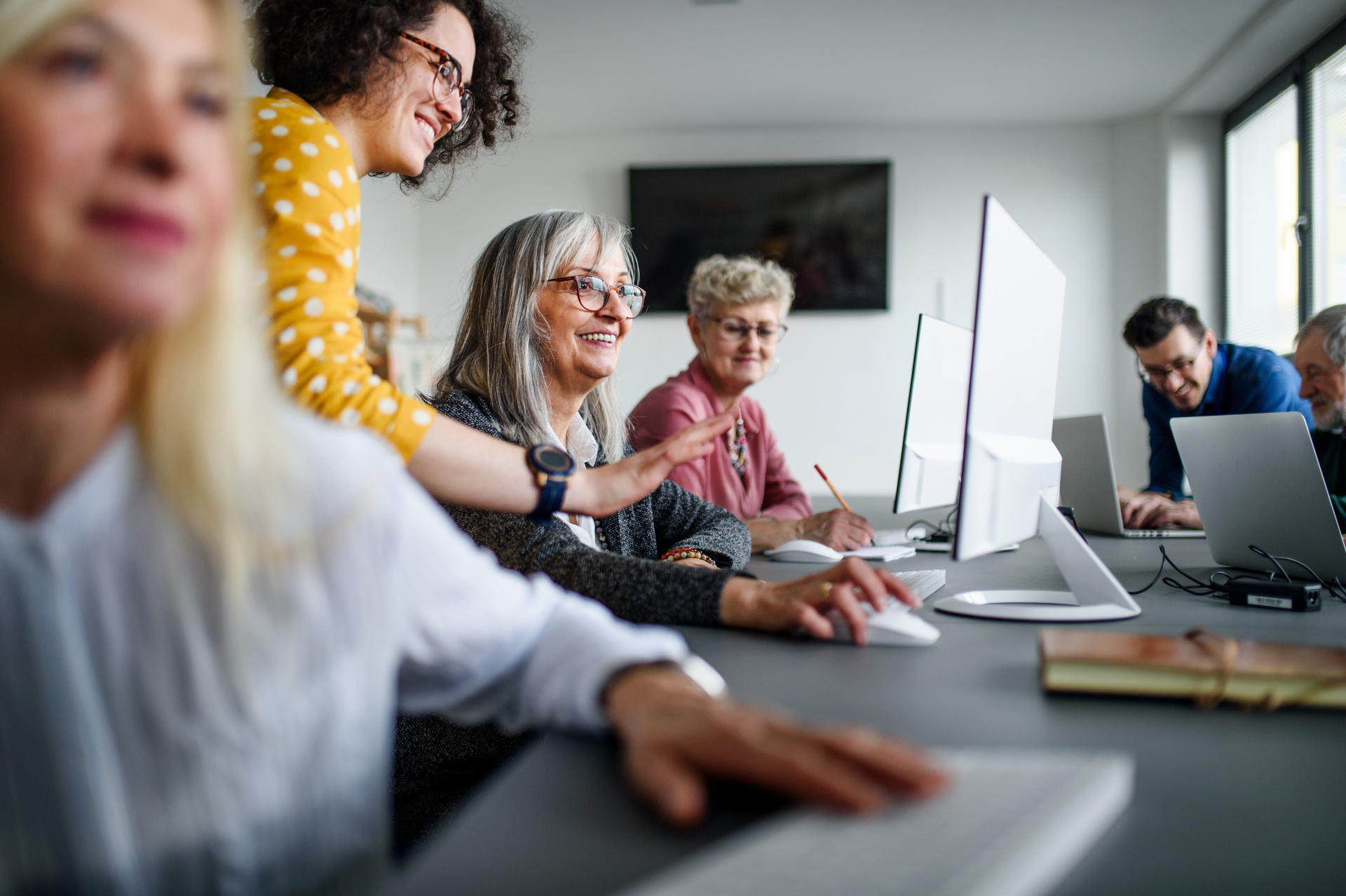 Eine Gruppe gut gelaunter Senioren besucht einen Computer- und Technologiekurs.