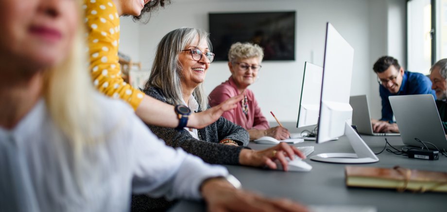 Eine Gruppe gut gelaunter Senioren besucht einen Computer- und Technologiekurs.