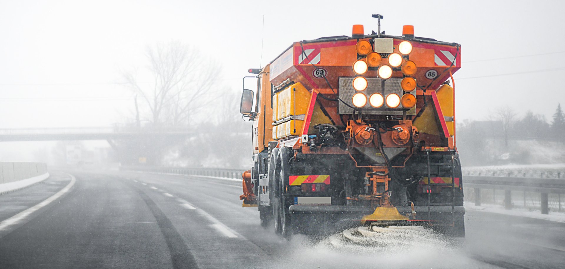 Winterdienstfahrzeug streut Salz auf einer Straße im Winter.