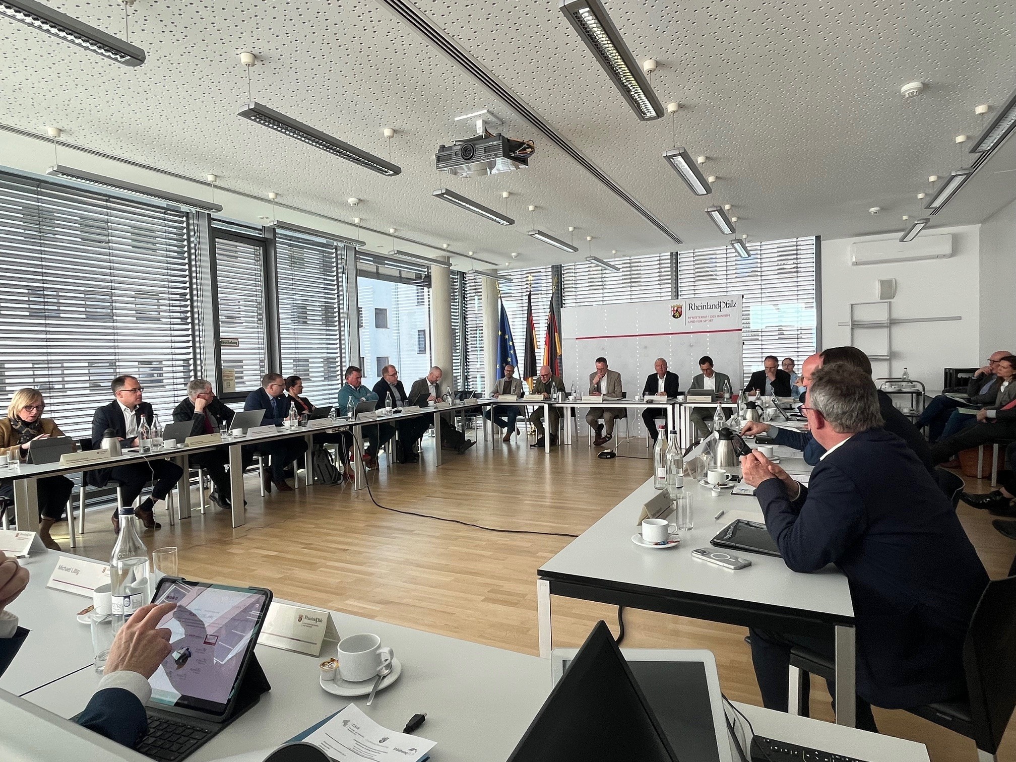 Mitglieder des Kommunalen Rates an Tischen in einem Sitzungssaal.