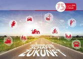 Straße mit der Aufschrift "Kommune schafft Zukunft". Die Straße ist umgeben von grüner Landschaft. Über ihr schweben rote Icons zum Thema Zukunft.