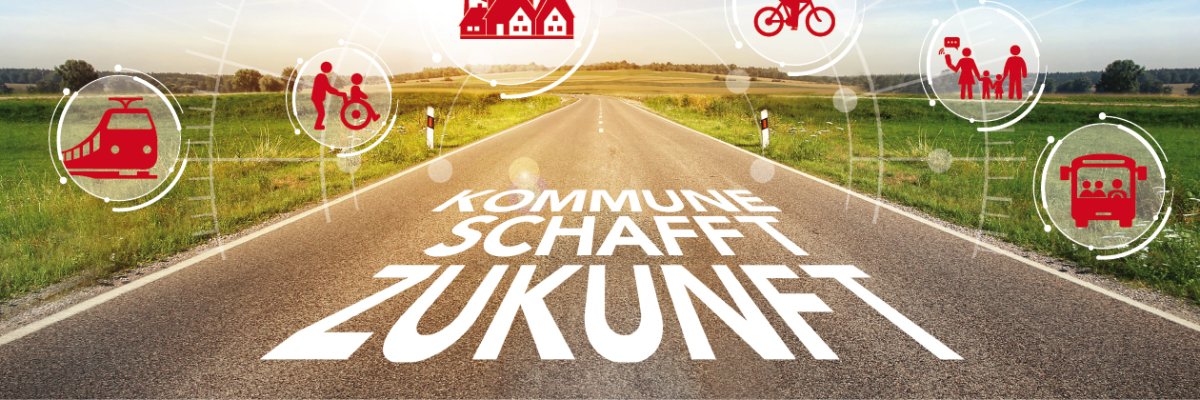 Straße mit der Aufschrift "Kommune schafft Zukunft". Die Straße ist umgeben von grüner Landschaft. Über ihr schweben rote Icons zum Thema Zukunft.