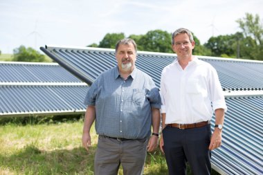 Ortsbürgermeister Volker Wichter und Michael Uhle, Klimaschutzmanager im Rhein-Hunsrück-Kreis, vor dem Solarthermie-Feld, welches das Nahwärmenetz von Neuerkirch-Külz unterstützt.  Bild: Energieagentur Rheinland-Pfalz