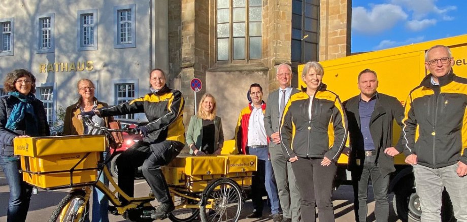 Die Deutsche Post DHL hat unter anderem E-Trikes und Elektro-Lastwagen im Einsatz. Vor dem Trierer Rathaus präsentieren Tanja Lauer (ver.di), Julia Hollweg (Klimaschutzmanagerin Stadt Trier), Zustellerin Katja Rößel, MdB Verena Hubertz, Thomas Schneider (Post-Betriebschef), OB Wolfram Leibe, Niederlassungsleiterin Anke Podewin, Sylvester Swierczynski (Betriebsratsvorsitzender) und Matthias Petersmarck (Zustellungsleiter für Trier) die umweltfreundlichen Fahrzeuge. Bild: Presseamt Trier