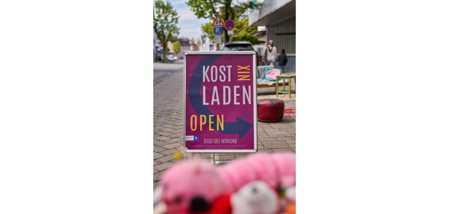 Aufsteller an der Straße macht auf den KostNixLaden aufmerksam.