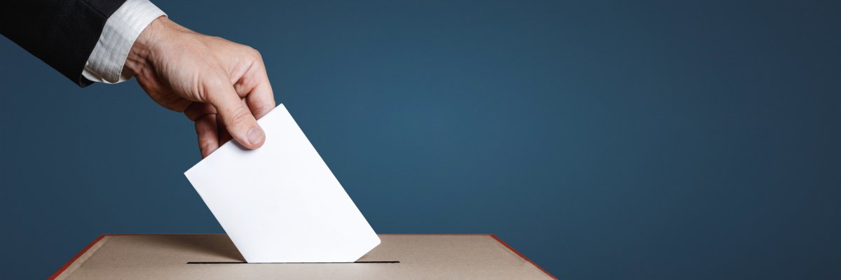 Voter hand puts the ballot into the ballot box. The concept of democracy and elections